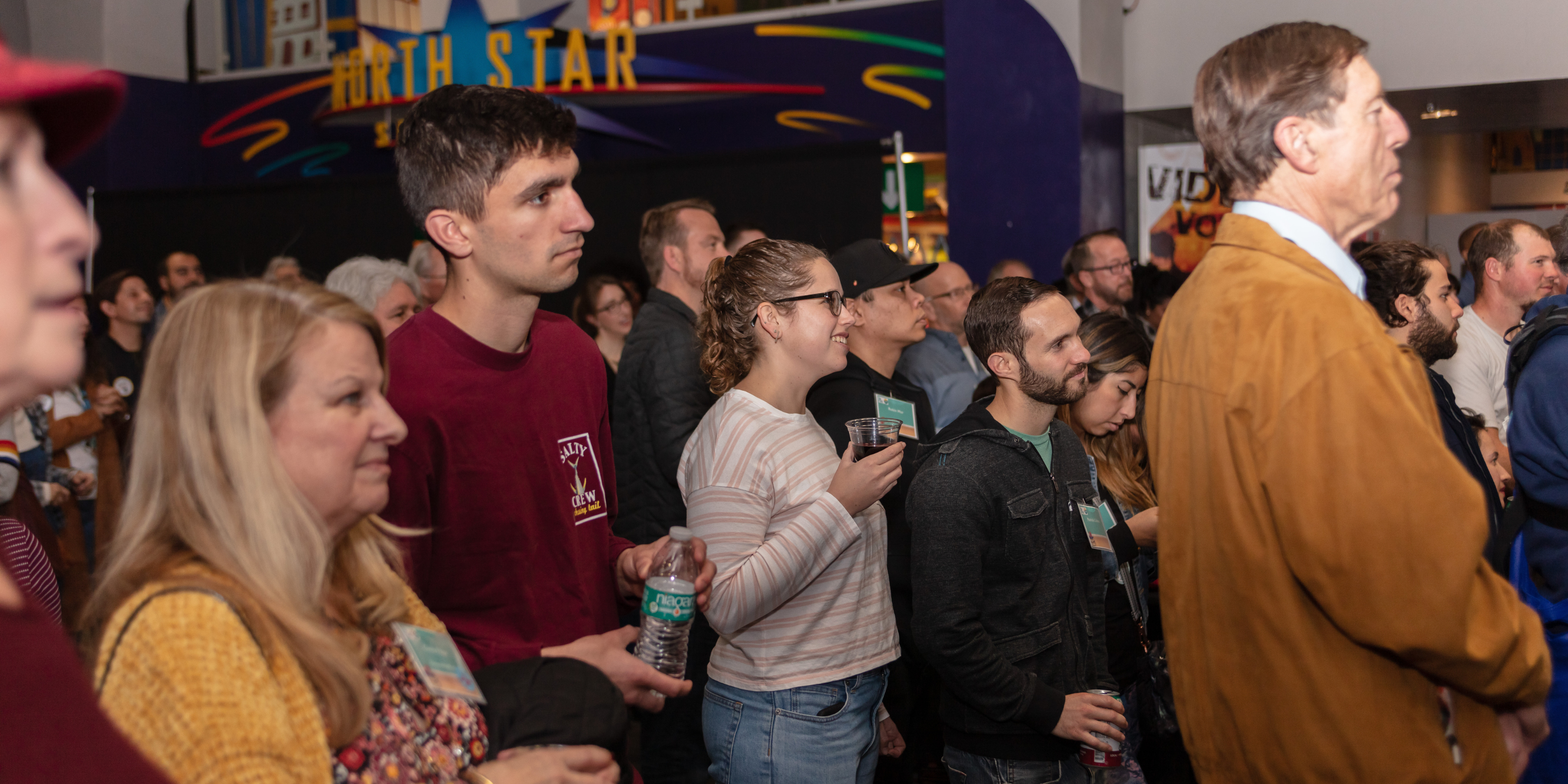 People gathered inside of the IMAX lobby of the Fleet Science Center with the North Star Science Store sign in the background.