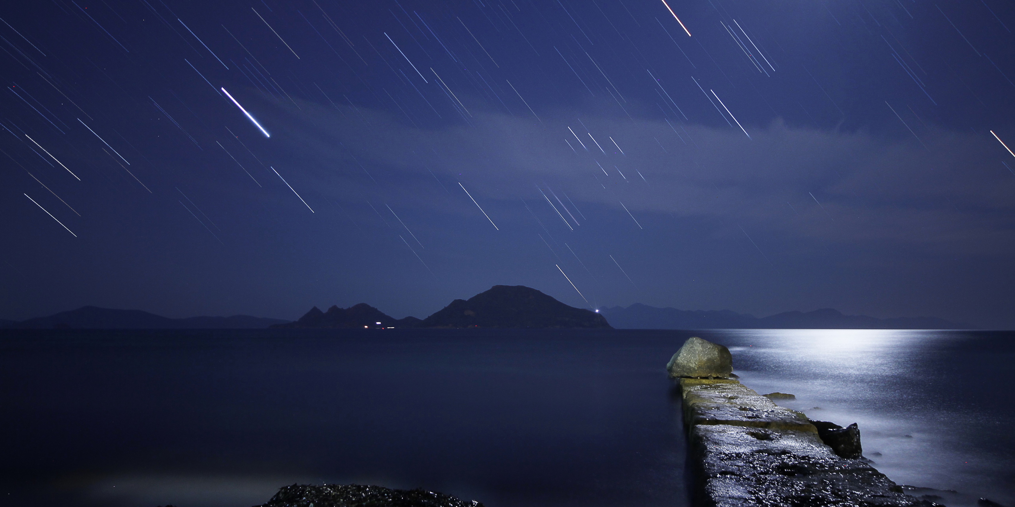 Image of the Perseid meteor shower over the ocean in moonlight.