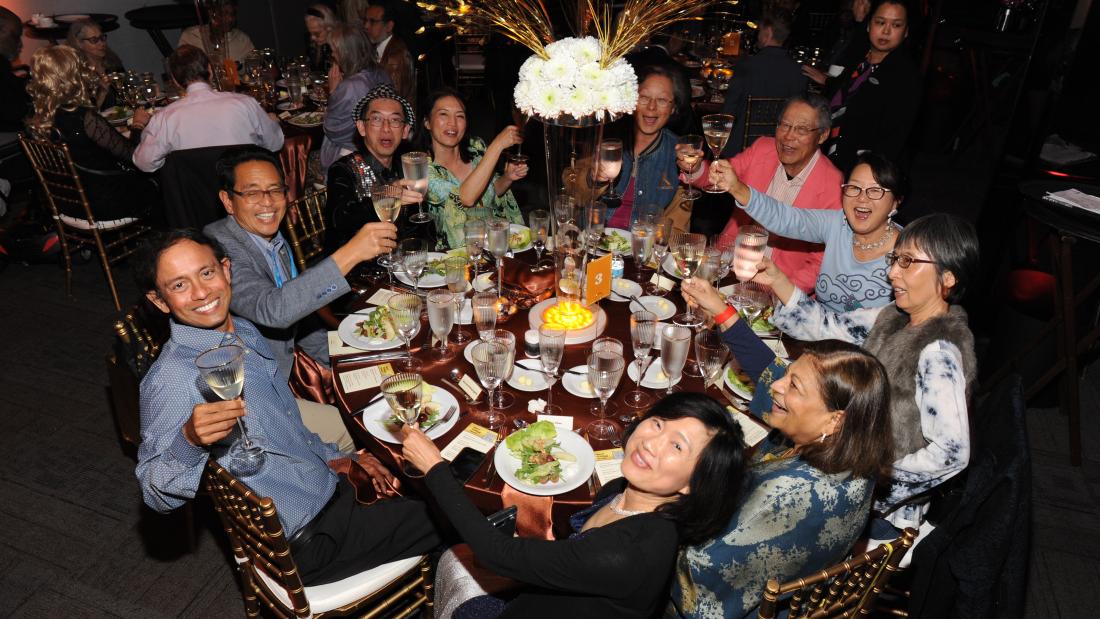 A group of people toasting at a round sparkling gala table