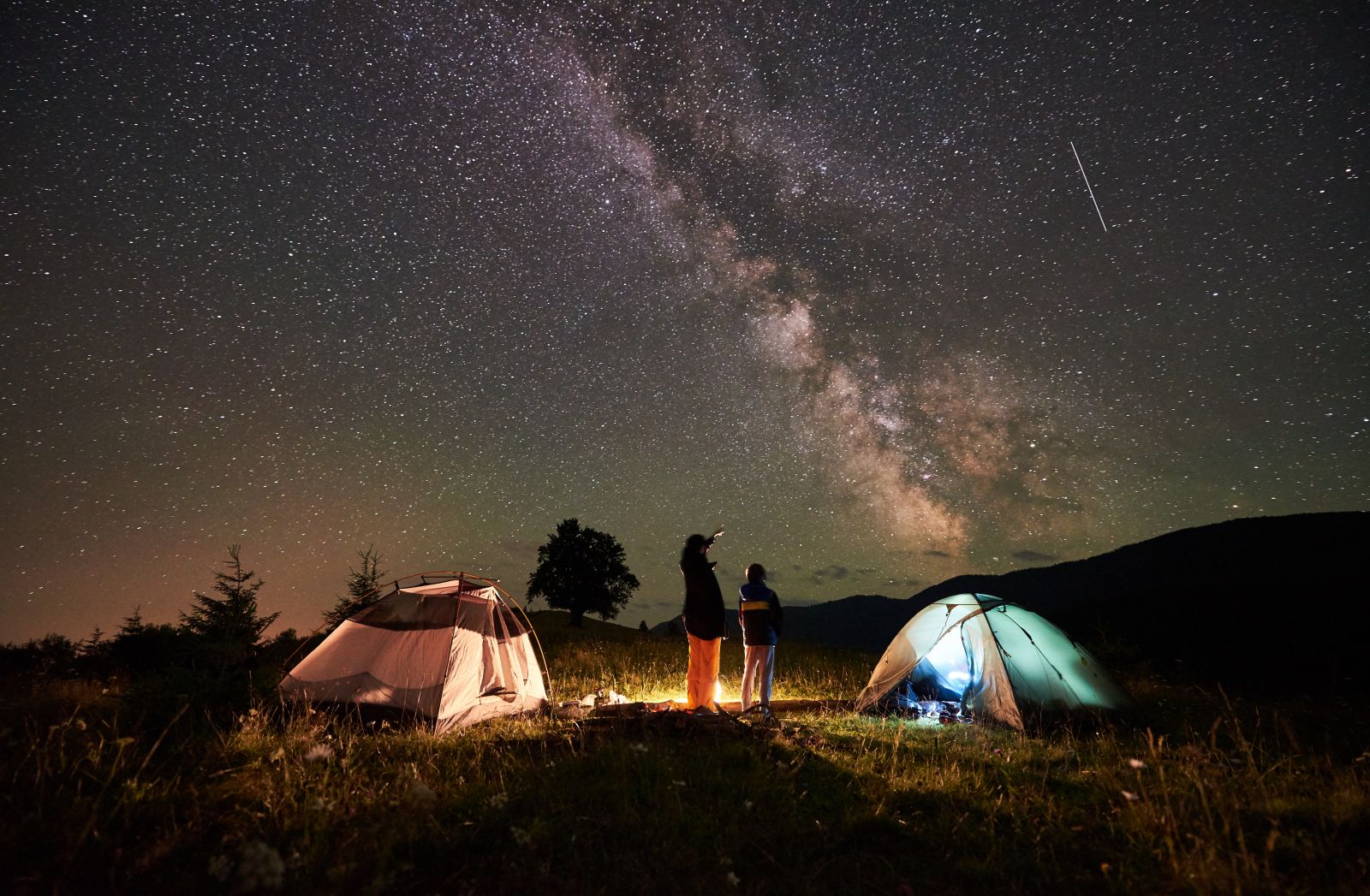 campers stargazing near their tents and fire