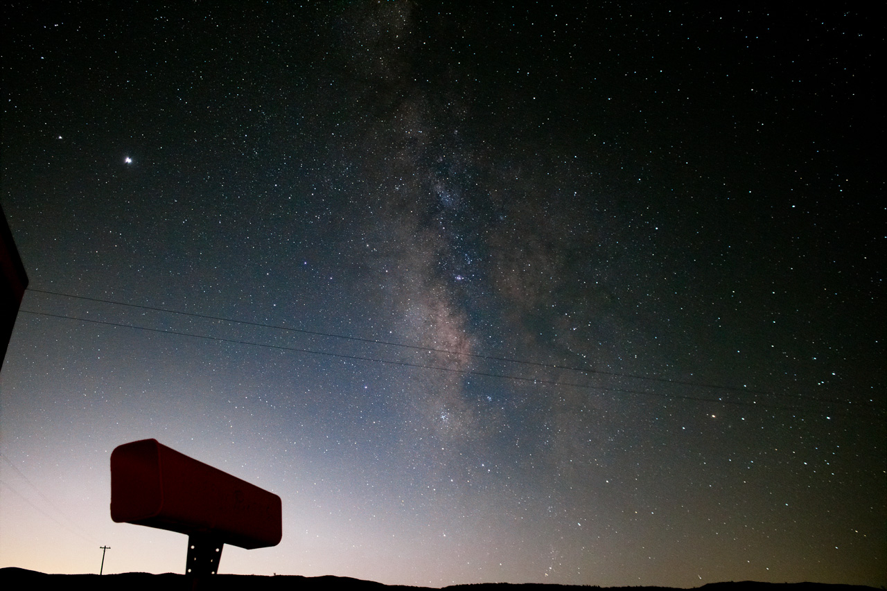 image depicts the night sky with a galaxy like star cluster visible. In the foreground is a viewing device used for stargazing.