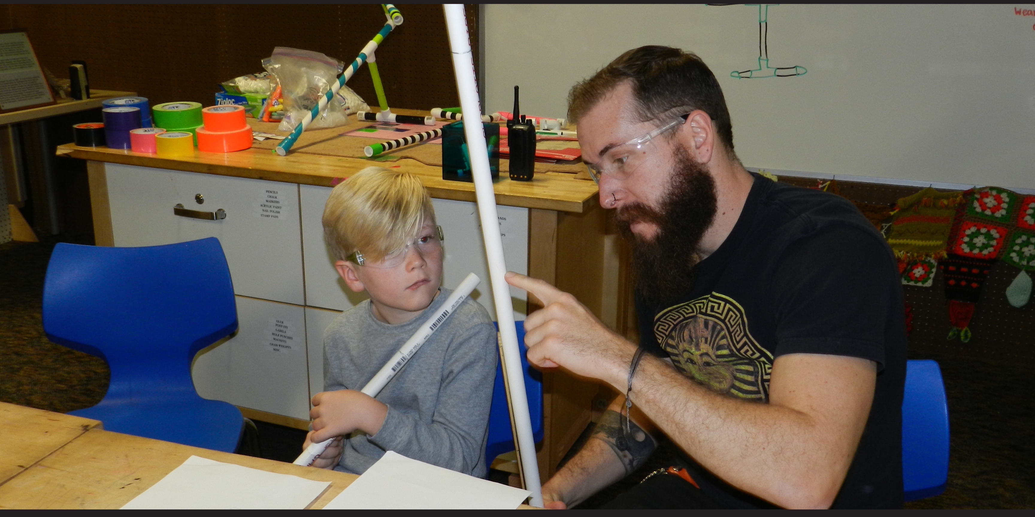 Young child and adult measure and work with pvc pipe in the tinkering studio at the Fleet Science Center.