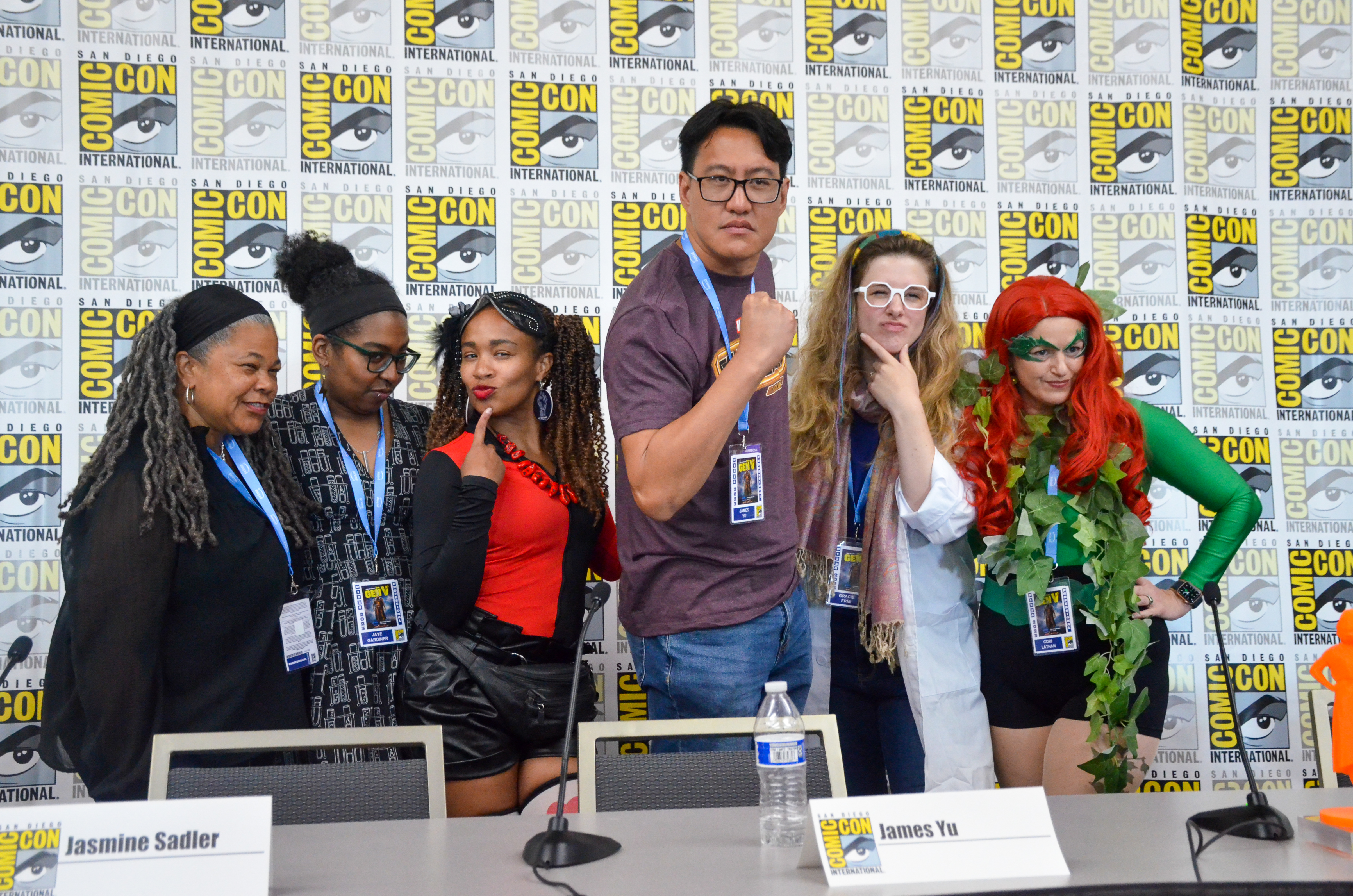 Group of six people stand together with a Comic-Con backdrop