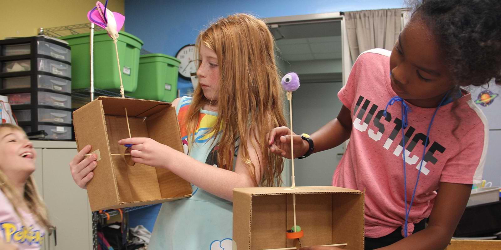 Three young girls having fun and building boxes with recycled materials