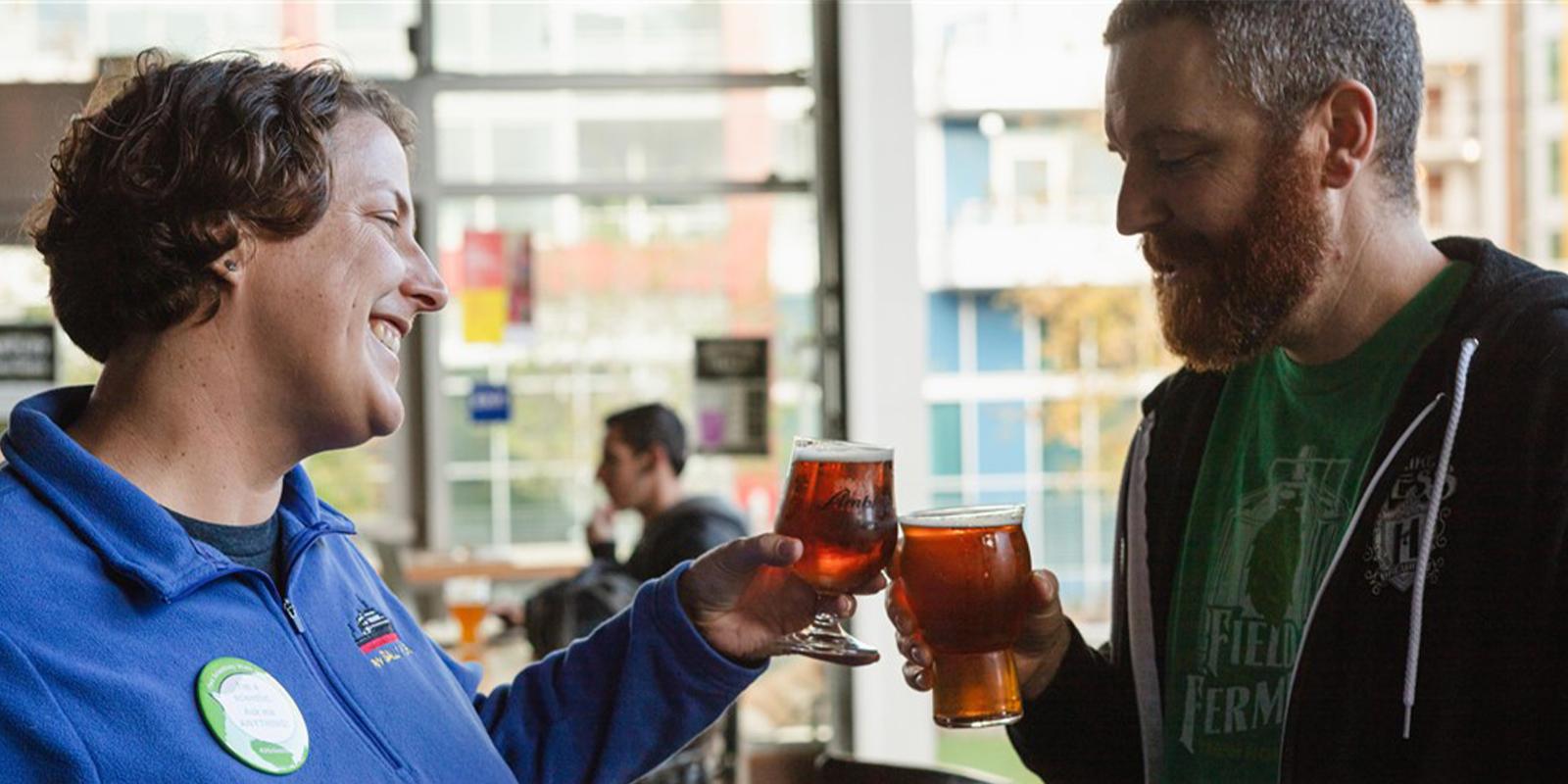 A man and a woman cheers craft beer in glasses
