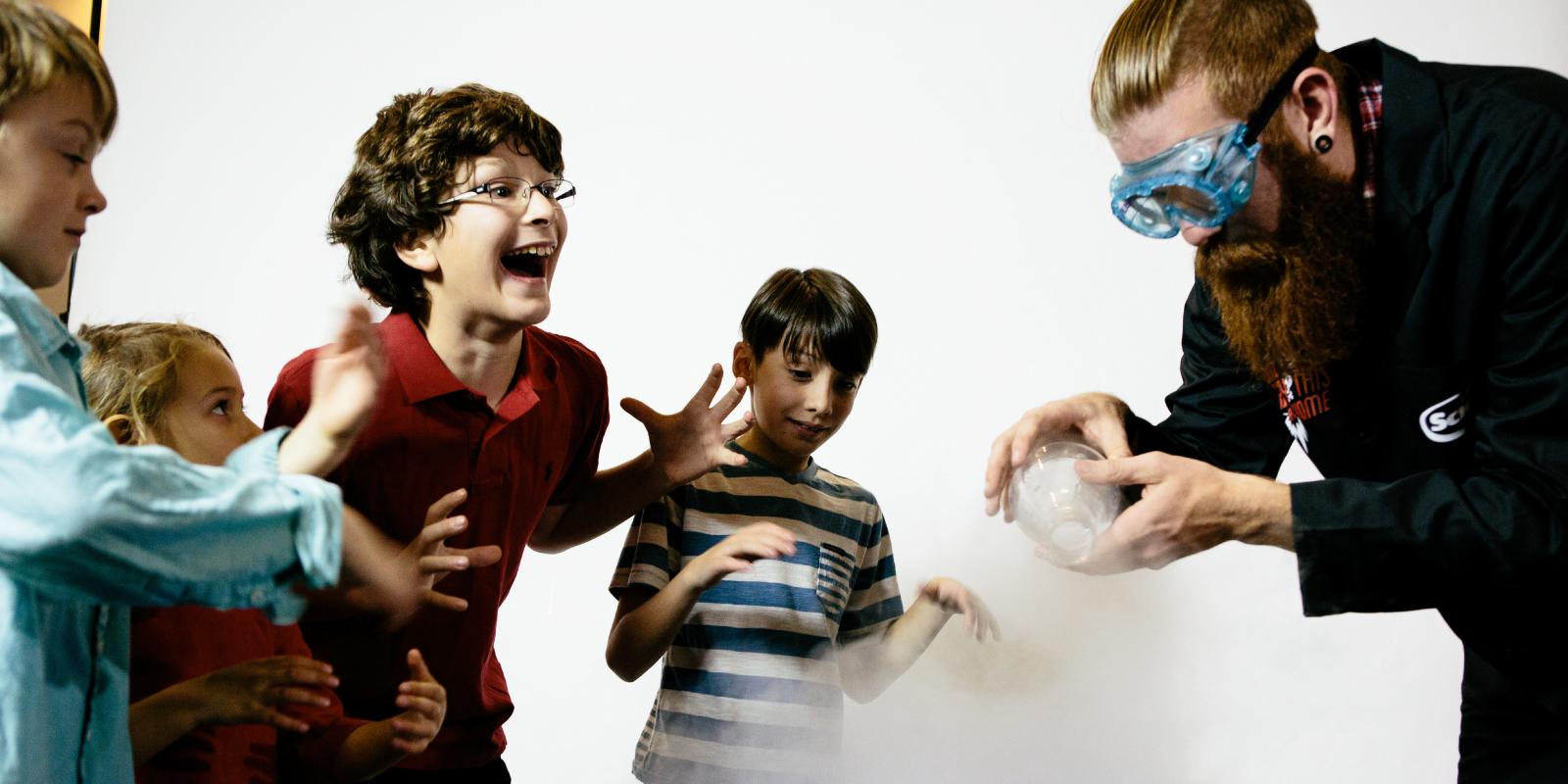 Four children having a blast while an adult is showing how to play with dry ice.