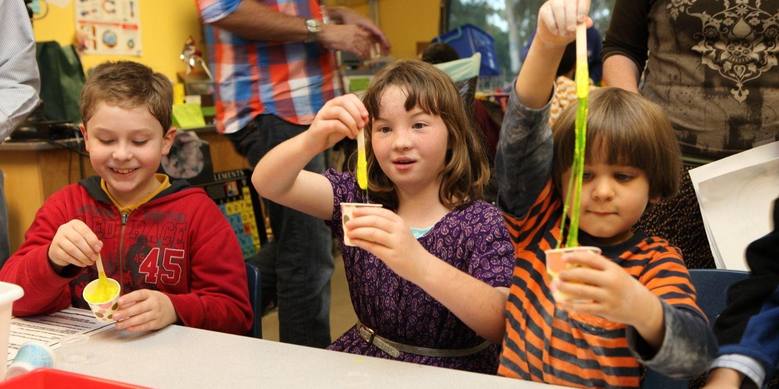 children play with slime inside a classroom at the fleet science center
