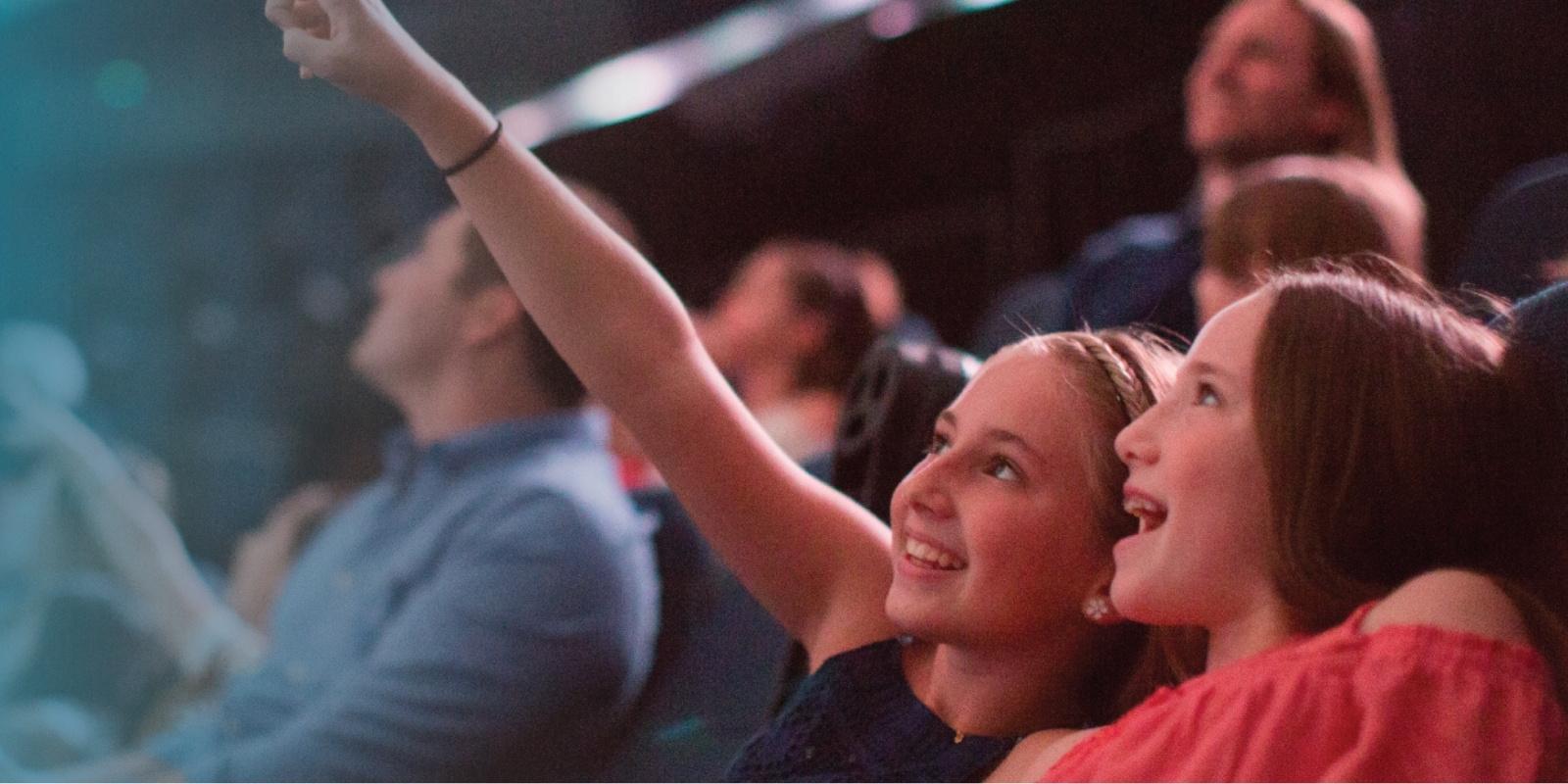 Two girls inside iMax theater point at screen