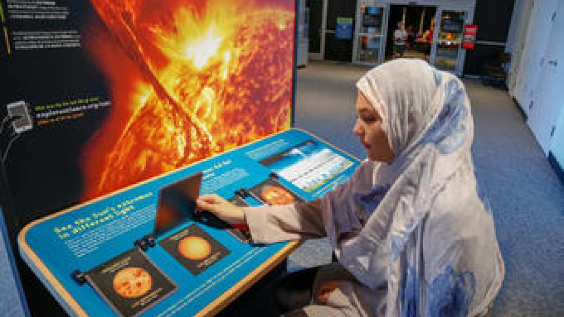 Woman interacting with exhibit at the Sun, Earth, Universe experience