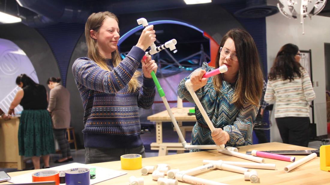 Two adult women building with wooden dowels at the Fleet Science Center