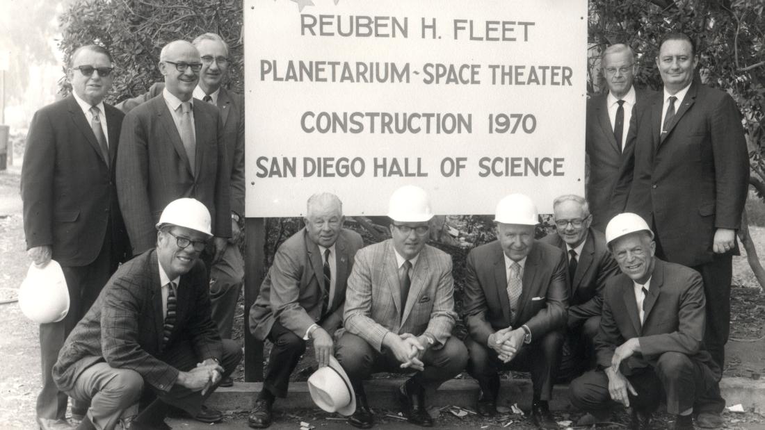Group of men in hard hats posing in from of the 1970s construction zone sign