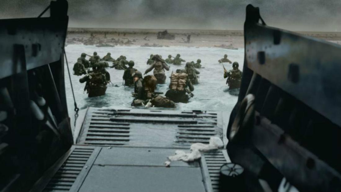 An iconic photograph taken from inside a water landing tank. WWII soldiers run out the open gate into ocean water and towards battle.