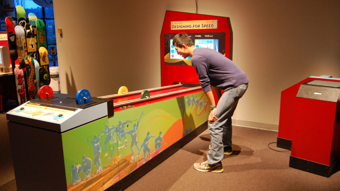 A man bent down in front of the Design Zone interactive "Designing for Speed."