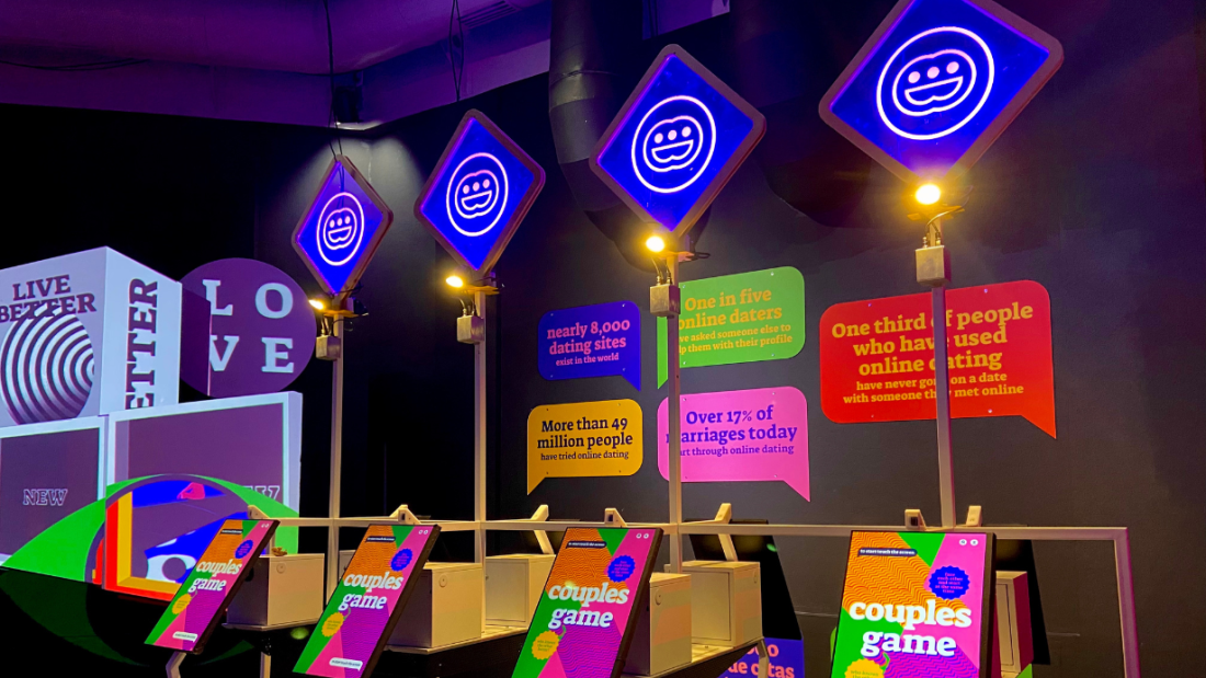 Photo of the Digital Me exhibition showing four stations with text that reads "couples game."