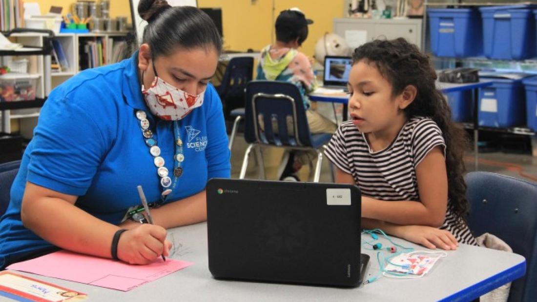 Fleet Science educator working with a student with a laptop.