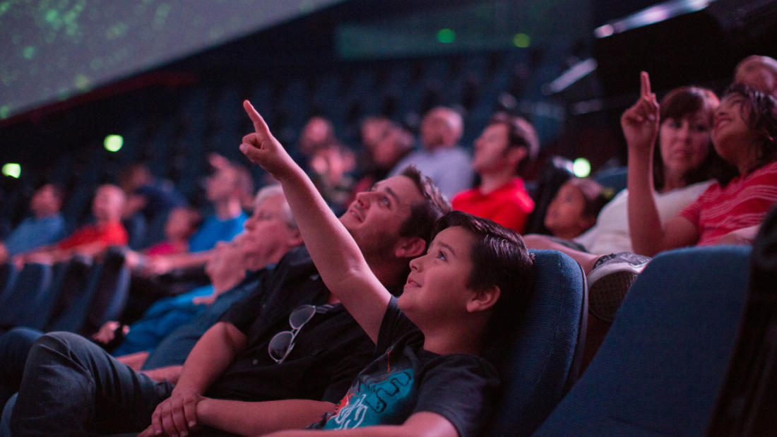 Photo of a young boy pointing up at at the screen in the giant dome theater.