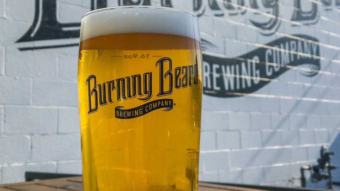 Full glass of beer with the text "Burning Beard Brewing Company"