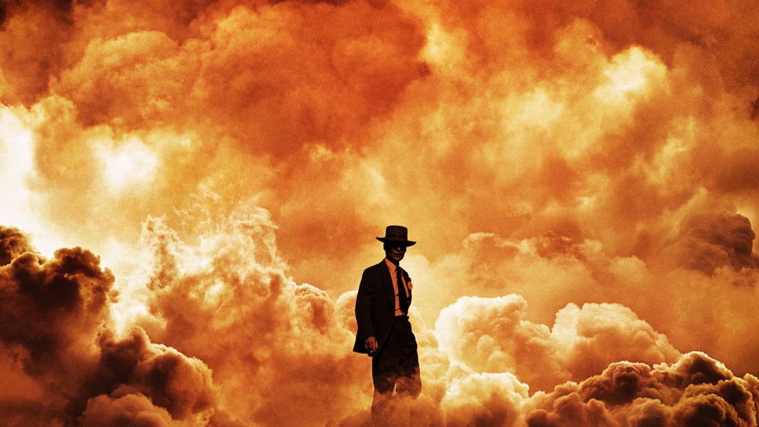 A man in a dark suit and hat standing in a fiery explosion, with orange and yellow cloudy smoke