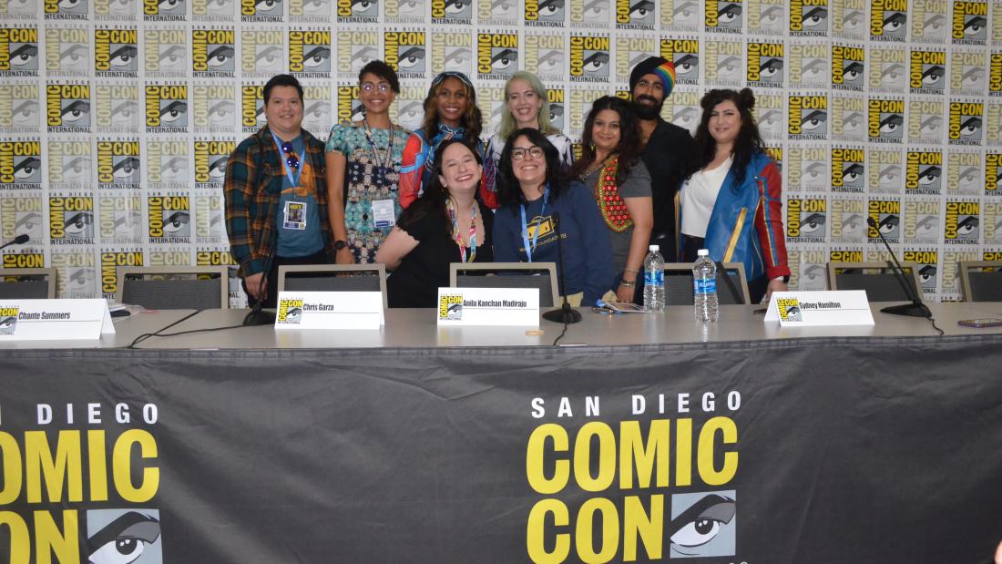 Group of people pose in front of a table that reads San Diego Comic-Con International