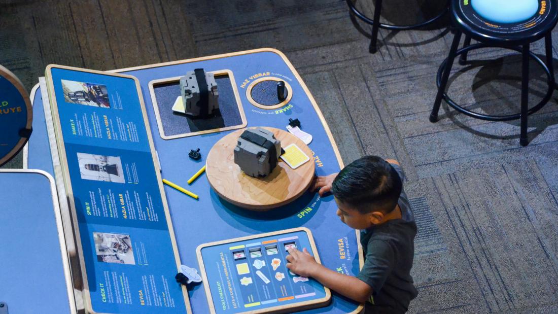 An aerial view of a young boy interacting with a blue exhibit 