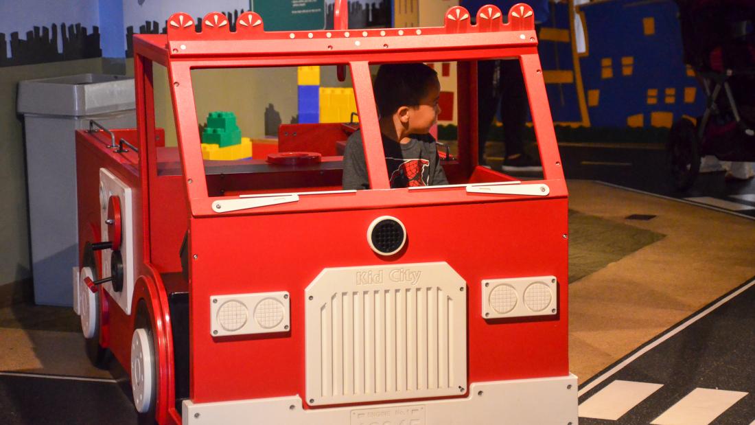 A child plays in a miniature firetruck