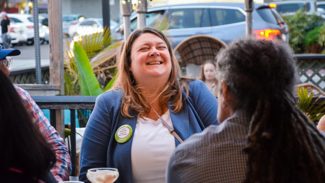 A woman laughing outside a bar head thrown back
