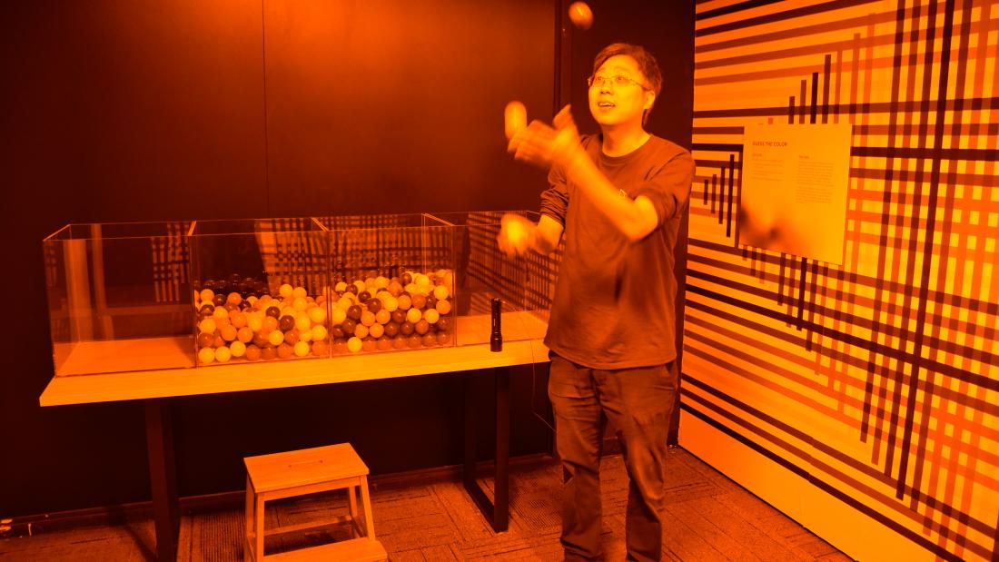 A man tossing a ball into the air in a room that makes everything look shades of brown