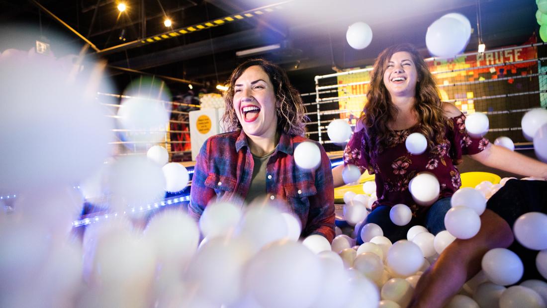 Two women playing in a white ball pit