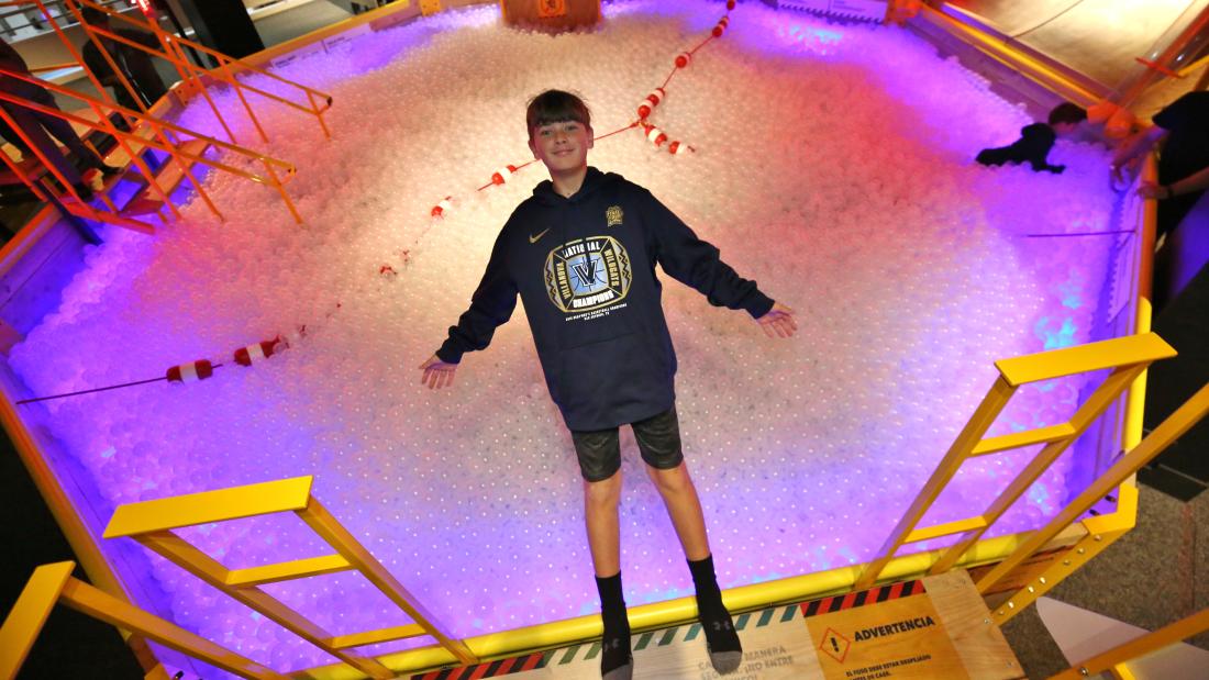 A boy falling backwards into a white ball pit