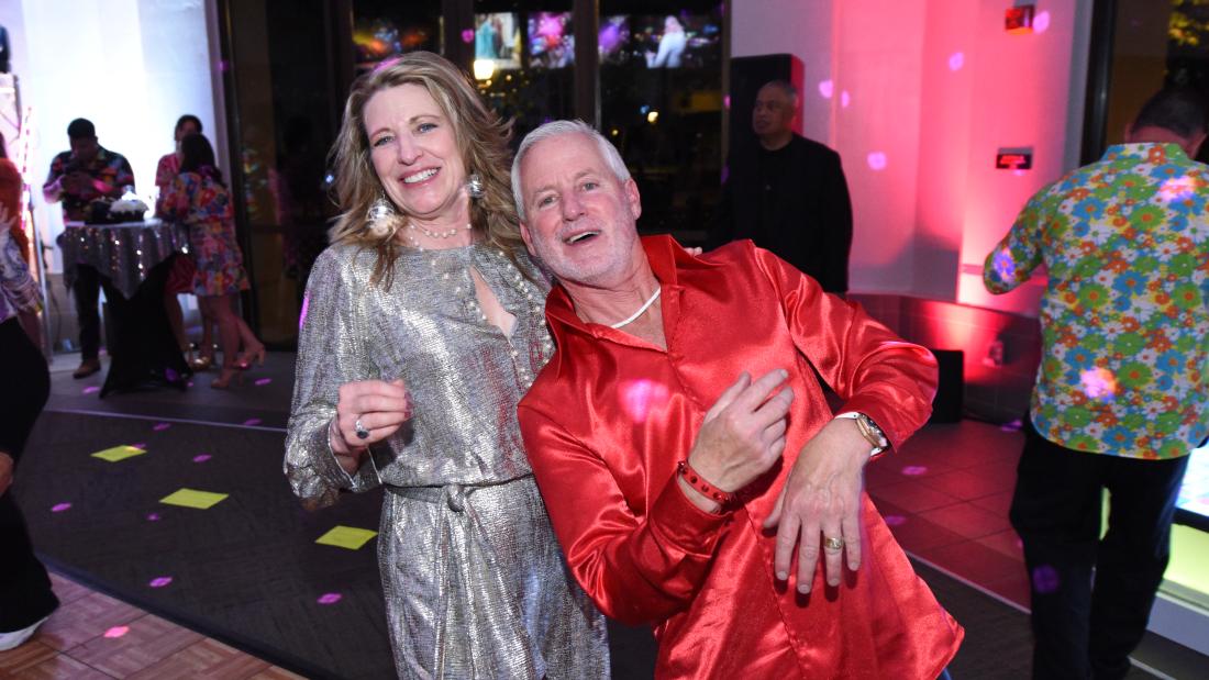 A man leans against a woman on a dance floor