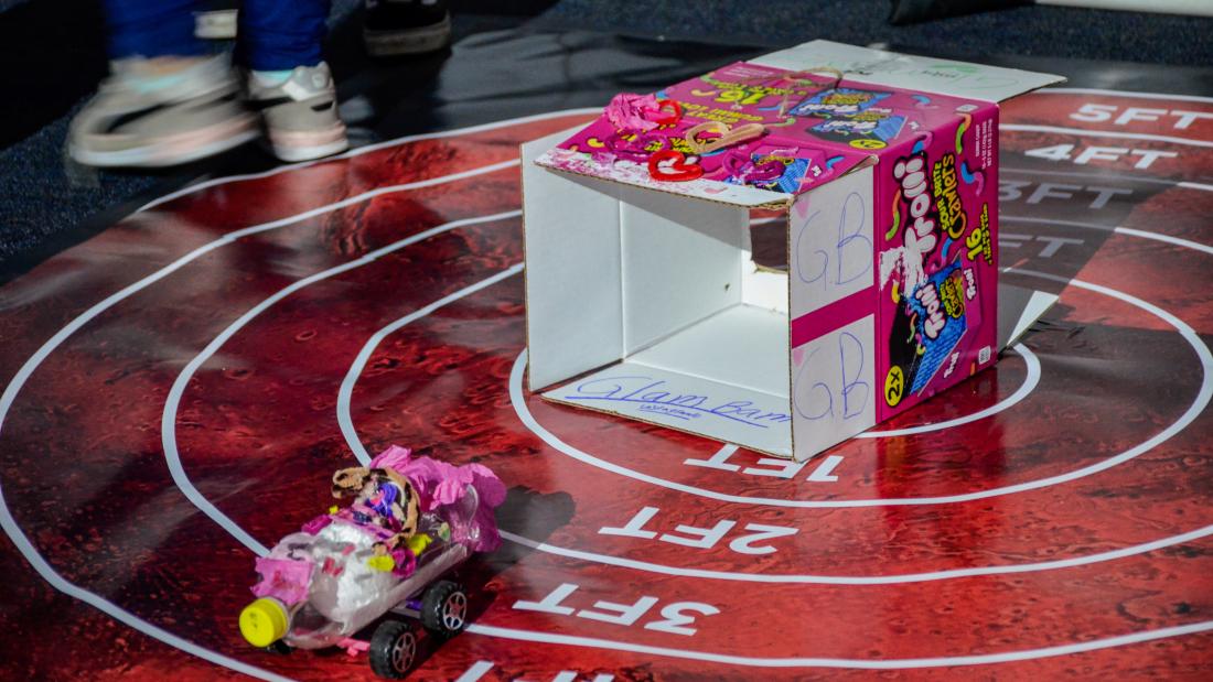 A science project mars rover made of a plastic bottle rolling out of the box it landed in