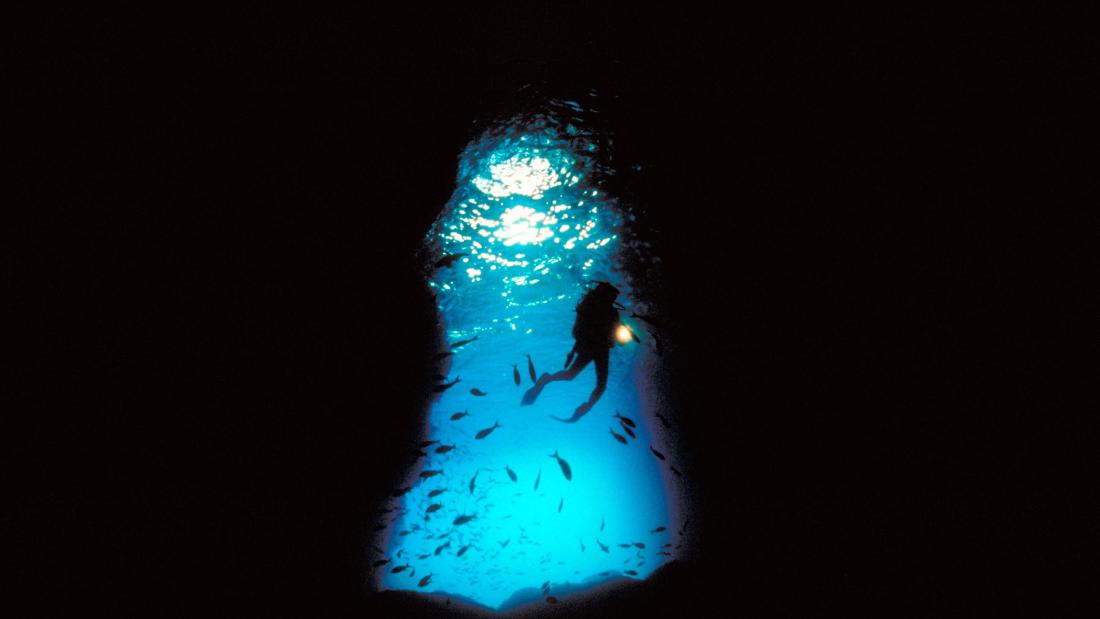 Still from the film Galapagos - A diver at the mouth of an underwater cave