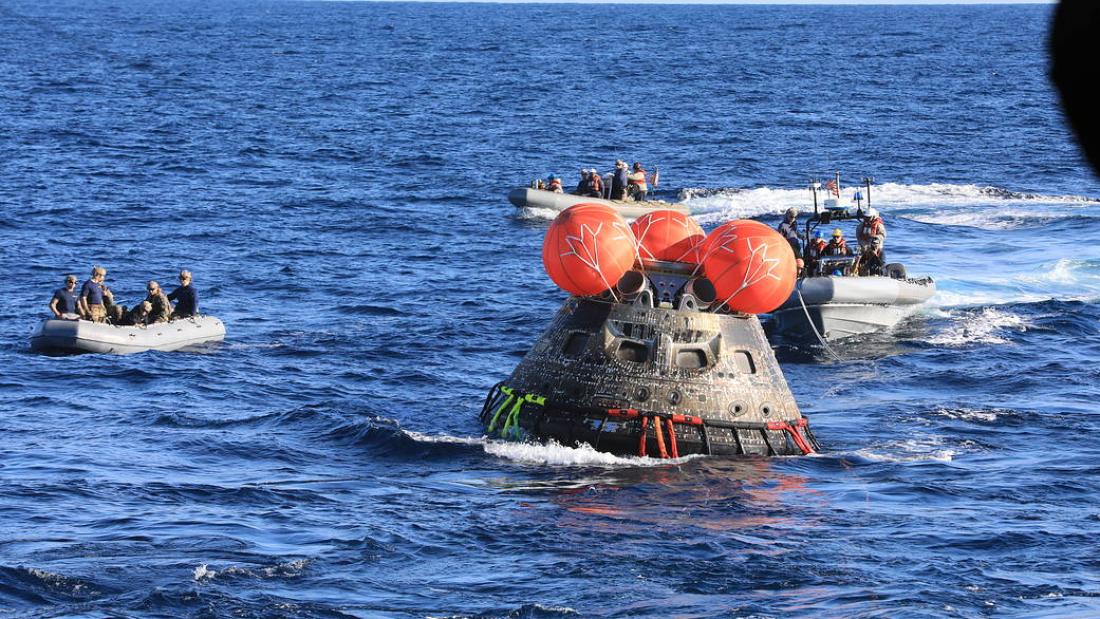 Orion capsule floating in Pacific Ocean surrounded by recovery crews