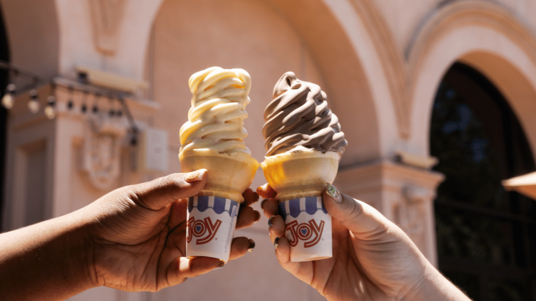Two ice cream cones cheersing in front of building