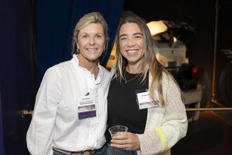 Two women smile posing next to each other