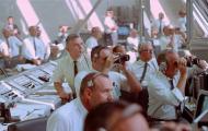 NASA managers Walter Kapryan (leaning on console), Rocco Petrone (with binoculars, center), and Kurt Debus (with binoculars, right) watch from Kennedy's Launch Control Center.