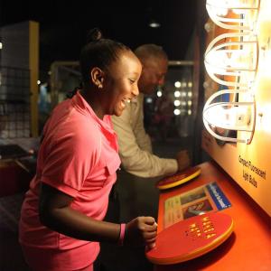 Middle school aged girl with adult man playing with a lightbulb exhibit