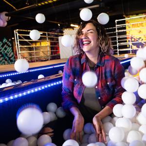 Woman playing in a ball put and throwing balls into the air while laughing