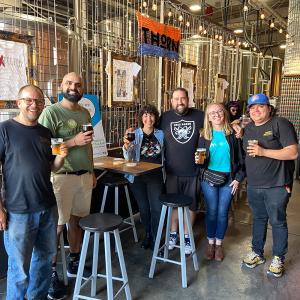 A group of people pose in a brewery and smile at the camera