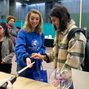 Two teenage girls look on with surprise while experimenting with static electricity 