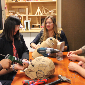 Five adults surrounding a table experimenting with cardboard materials as they build items