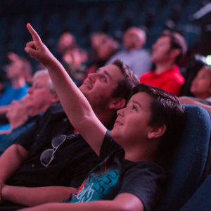 Young child pointing upwards towards the screen inside of the Heikoff Giant Dome Theater.