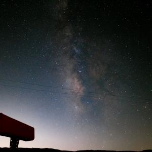 image depicts the night sky with a galaxy like star cluster visible. In the foreground is a viewing device used for stargazing.