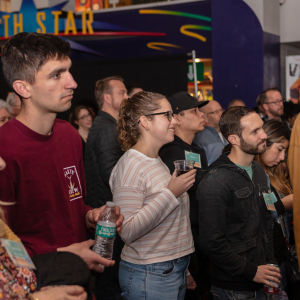 People gathered inside of the IMAX lobby of the Fleet Science Center with the North Star Science Store sign in the background.