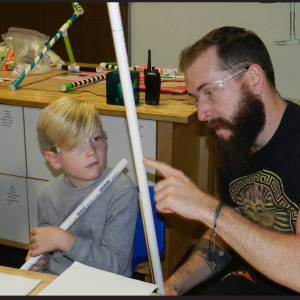 Young child and adult measure and work with pvc pipe in the tinkering studio at the Fleet Science Center.