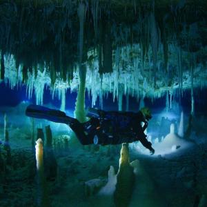 A scuba diver swims through a narrow crevasse in an underwater cave.