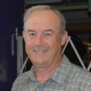 A middle aged white man with short grey hair smiles toward the camera.