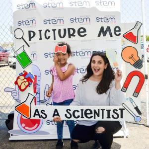 Mom and daughter posing behind a frame that reads "picture me as a scientist"