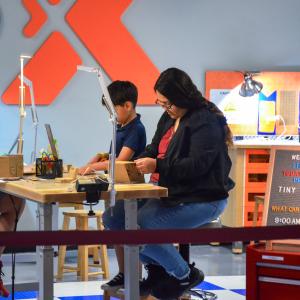 Adult woman and two male teens working at a table with tools