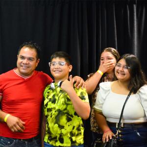 A man with a boy and two girls smile with arms around each other posing for a photo